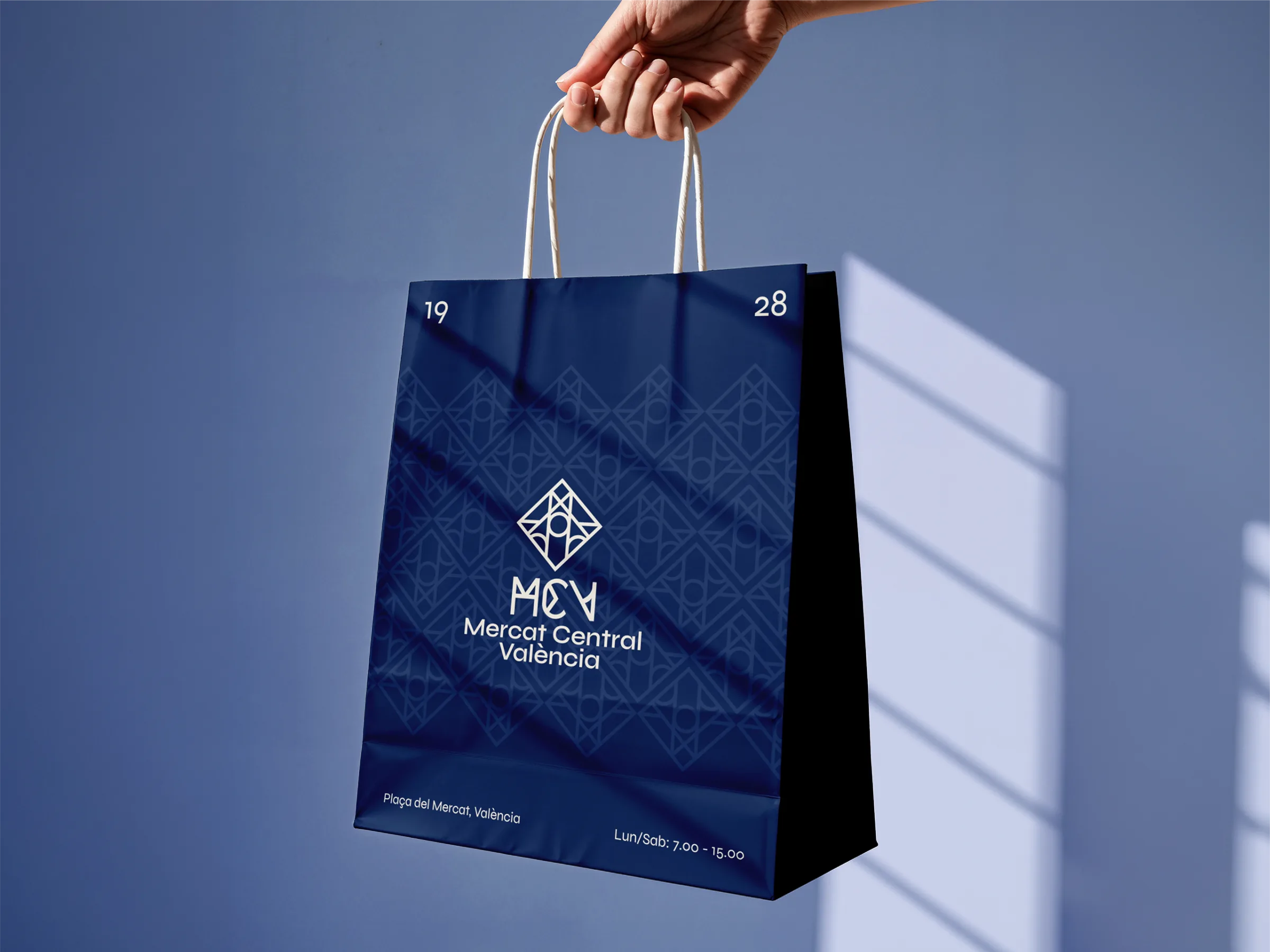 Mercat Central paper shopping bag held against a blue wall